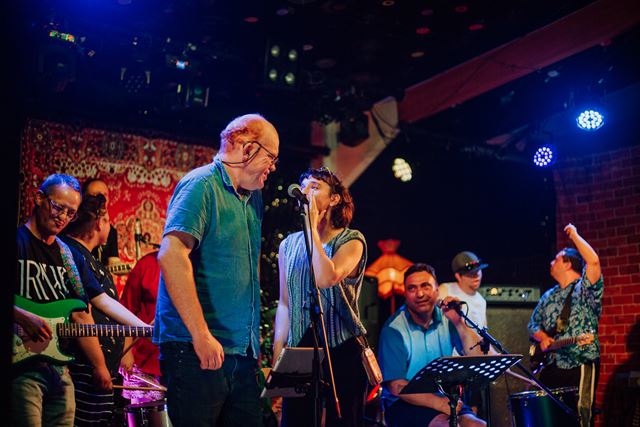 A stage full of people singing and playing instruments 
