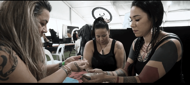 A Māori artist takes part in a smudging ceremony before receiving tattoo work from an indigenous Canadian artist as another indigenous artist supports