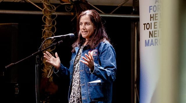 Woman in denim jacket speaks into a microphone